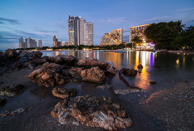 River by illuminated buildings against sky at night