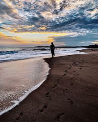 Man on beach against sky during sunset