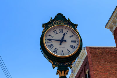 Low angle view of clock against clear sky