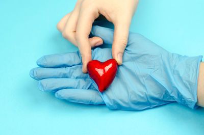 Midsection of man holding heart shape against blue background