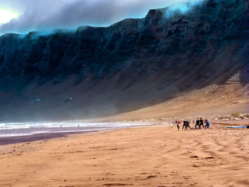 People on beach against mountains
