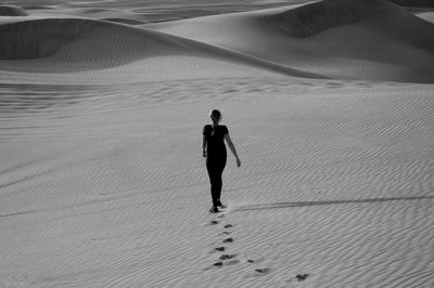 Rear view of mature woman walking on sand dune in desert