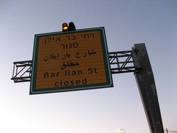 Low angle view of road sign against clear sky