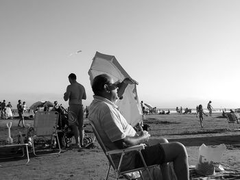 People at beach against clear sky