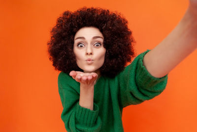 Portrait of young woman against yellow background