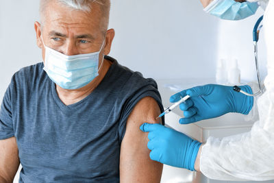 Doctor vaccinating senior man in clinic. elderly people vaccination. covid19 coronavirus vaccine