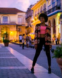 Full length portrait of woman on illuminated city at night