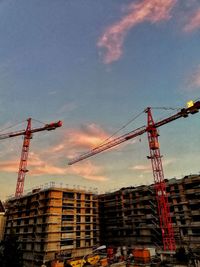 Low angle view of cranes at construction site against sky