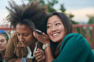 Friends listening mobile phone during social gathering on terrace