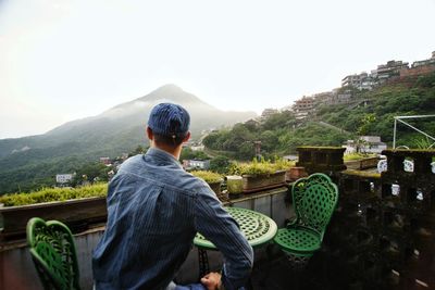 Rear view of man looking at mountain against sky