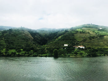 Scenic view of river by mountains against sky