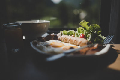 Close-up of breakfast served in plate on table against window