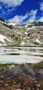 Scenic view of lake by snowcapped mountain against sky