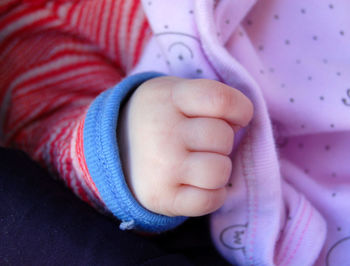 Cropped hand of baby on bed at home