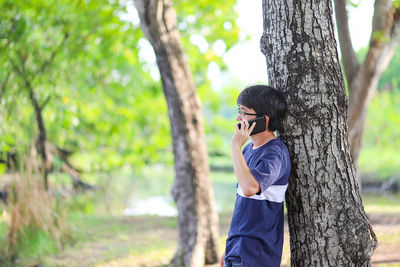 Side view of boy climbing on tree trunk