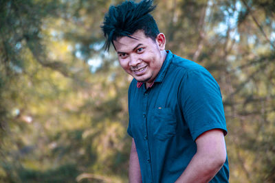 Portrait of young man standing against trees