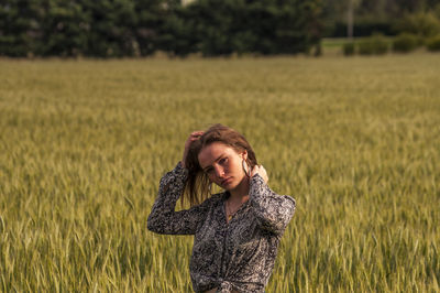 Portrait of young woman standing on agricultural field