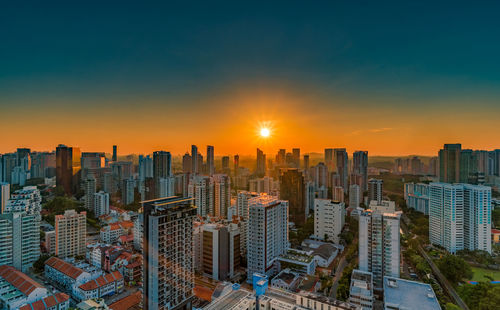 Modern buildings in city against sky during sunset