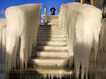 Low angle view of man standing on snow covered staircase