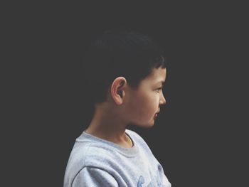 Portrait of boy looking away against black background