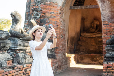 Cheerful woman doing selfie while standing against temple