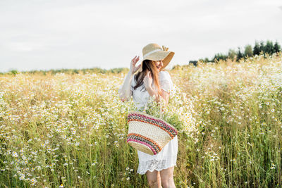 Woman standing on flowering field against sky