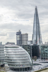 Modern buildings in city against cloudy sky