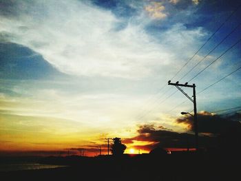 Power lines against cloudy sky