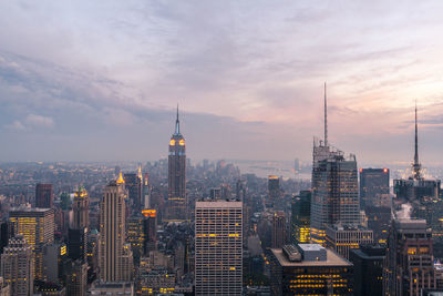 Aerial view of buildings in city against cloudy sky