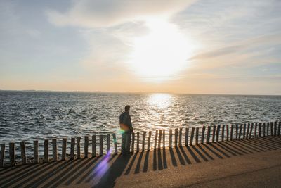 Rear view of man looking at sea against sky