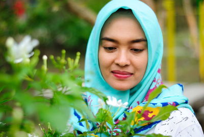 Close-up of woman wearing hijab looking at flower in park