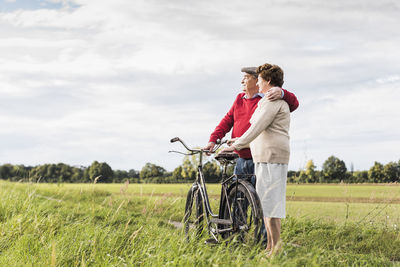 Senior couple with bicycles embracing in rural landscape
