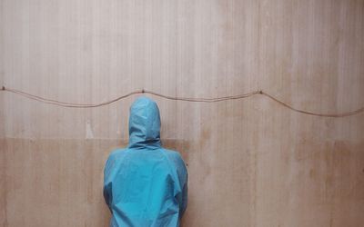 Rear view of a man standing against wall