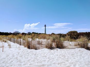 Lighthouse on field against sky during summer