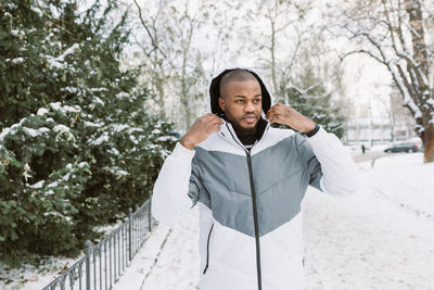 Young african man on street, snow winter season, city portrait