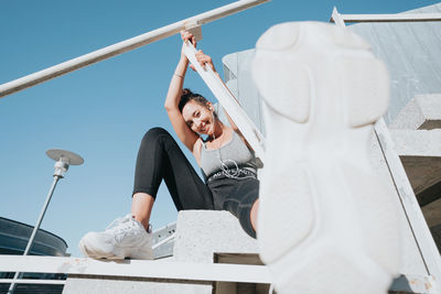 Low angle view of woman sitting on railing