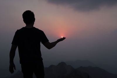 Silhouette man standing on mountain against sky during sunset