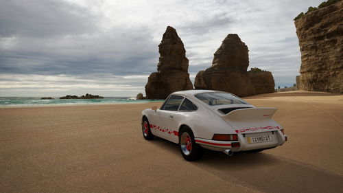 Vintage car on beach against sky