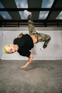 Full body of energetic young man doing acrobatic handstand while performing break dance