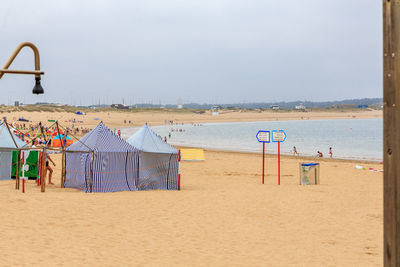 Deck chairs on beach against sky