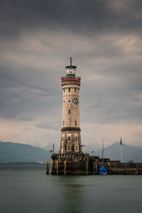 Lighthouse by building against sky