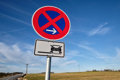 Road sign on field against blue sky