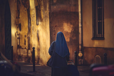 Rear view of woman wearing hijab standing indoors 