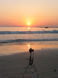 Man photographing on sea against sky during sunset