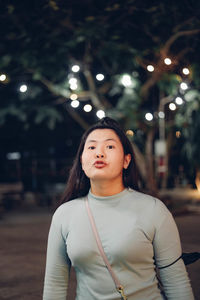 Portrait of young woman standing at night