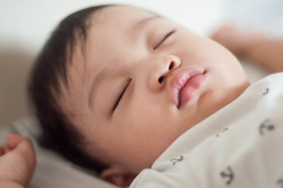 Close-up of cute baby boy sleeping on bed at home