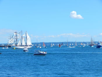 Sailboats sailing in sea against blue sky