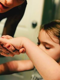 Close-up of woman holding daughter hand at home
