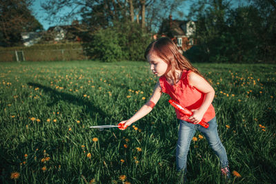 Full length of girl holding plant on field