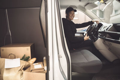 Portrait of happy driver with package sitting in truck